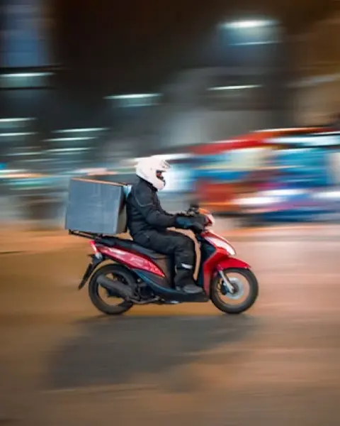 Courier riding a scooter with a delivery box