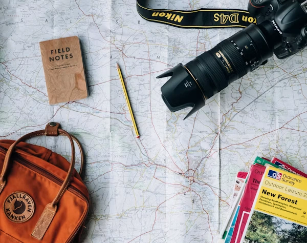 Travel planning map with camera, guidebooks and backpack