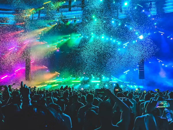 Music festival crowd celebrating with colorful stage lights and confetti